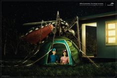 two people sitting in a tent next to an airplane