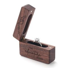 an engagement ring in a wooden box with the words, the adventure begins engraved on it