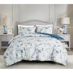 a bed with blue and white comforters in a bedroom next to two nightstands