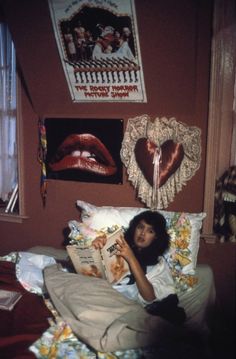 a young woman laying in bed reading a magazine - stock image, she is looking at the camera and smiling