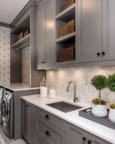 a washer and dryer in a kitchen with gray cabinets, marble counter tops