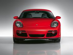 the front end of a red sports car with its lights on in a studio setting