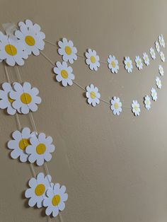 some white and yellow flowers are hanging on a wall with the word love spelled out