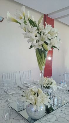 there is a vase with white flowers on the dining room table set up for an event