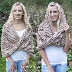 two beautiful women standing next to each other in front of some bushes and trees, one wearing a crocheted shawl