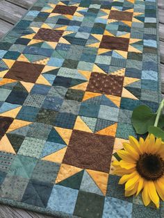 a sunflower sitting on top of a wooden table next to a patchwork quilt