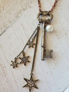 an antique key with five stars and pearls hangs from a chain on a wooden surface