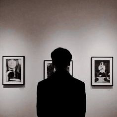 a person standing in front of some pictures on the wall with their back turned to the camera