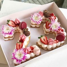 there are many desserts in the box on the table and one is decorated with flowers