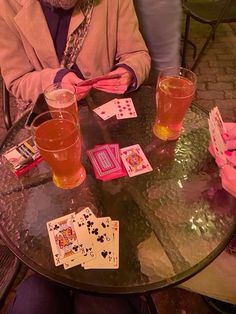 two people sitting at a table with cards and drinks