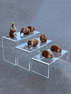 three clear acrylic tables with stuffed animals on them in the shape of tigers