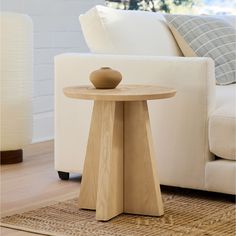 a small wooden table sitting on top of a rug in front of a white couch