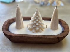 three small white candles sitting on top of a wooden tray