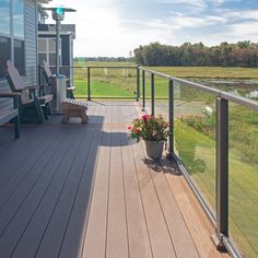 a balcony with chairs and flowers on the deck next to a lake in the distance