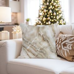 a living room with a christmas tree in the background and pillows on the couches