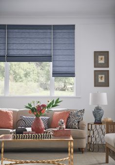 a living room filled with furniture and a window covered in blue roman blind shades on the windowsill