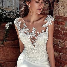 a woman in a wedding dress leaning against a brick wall