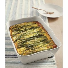 a casserole dish with asparagus in it on a striped place mat