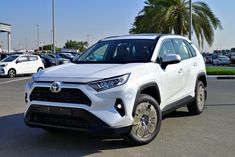 a white toyota rav parked in a parking lot with other cars and palm trees