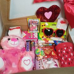 a pink teddy bear in a box filled with valentine's day treats and candy