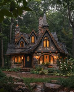 a small stone house in the woods lit up at night with windows and lights on