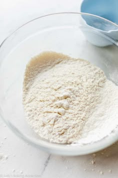 a glass bowl filled with flour next to two blue bowls