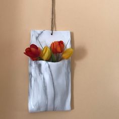 some flowers are in a marble bag hanging on a wall