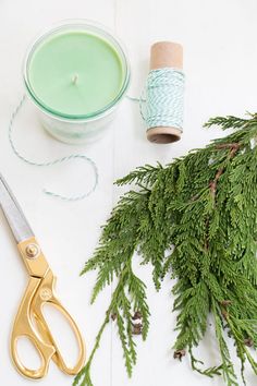 scissors, twine and spools of thread sitting next to a green candle