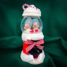 a snow globe with santa hats and stockings on it, sitting on a green cloth