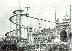 an old black and white photo of a man on a roller coaster in front of a building