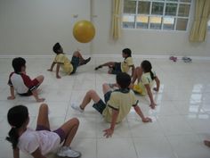 a group of children sitting on the floor playing with a ball