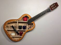 a guitar shaped like a shelf with items in it on top of a white wall