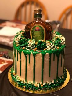 a cake with green icing and a bottle of liquor on top sitting on a table