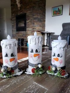 three snowman candles sitting on top of a wooden table