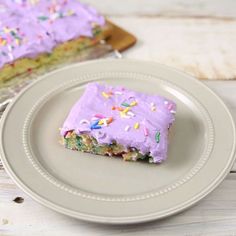 a piece of cake with purple frosting and sprinkles on a plate