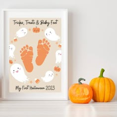 two pumpkins are sitting next to a white frame with a baby's footprints on it