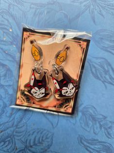 two cartoon character shaped keychains are in a package on a blue tablecloth