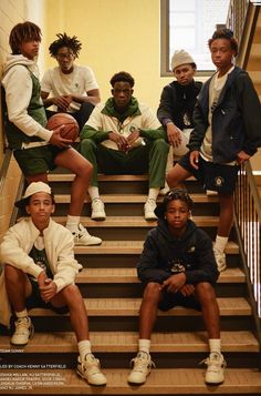 a group of young men sitting on top of stairs next to each other holding basketballs