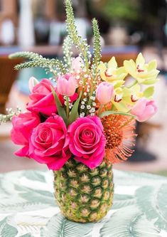 a pineapple vase filled with pink flowers on top of a table