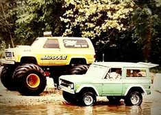 two monster trucks are parked in the mud