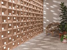 a chair and potted plants in front of a wall with geometric tiles on it