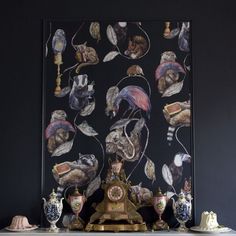 an ornate clock sits in front of a black wall with many different pictures on it