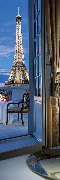 the eiffel tower is seen through an open window in this room with a table and chairs