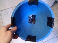 a person is holding up a blue bowl with black tape around the bottom and sides