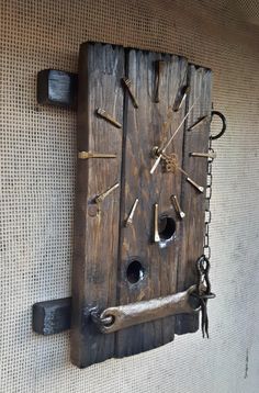 a clock made out of wood with chains hanging from it's sides on the wall