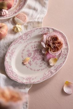 two plates with pink flowers on them and petals scattered around the plate, next to each other