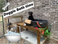 a black dog sitting in a bath tub on top of a wooden bench next to a brick wall