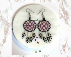 a pair of beaded earrings with stars on them sitting on top of a white plate