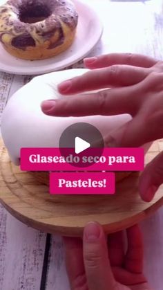 a person holding a doughnut on top of a wooden plate next to another donut