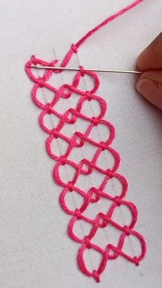 someone is working on a piece of fabric with yarn in the shape of heart shapes